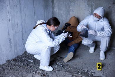 Photo of Forensic experts working at crime scene with dead body inside abandoned building