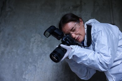 Photo of Forensic expert with camera working at crime scene inside abandoned building, low angle view. Space for text