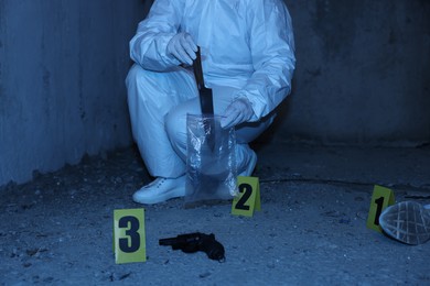 Photo of Forensic expert with evidence working at crime scene inside abandoned building, closeup