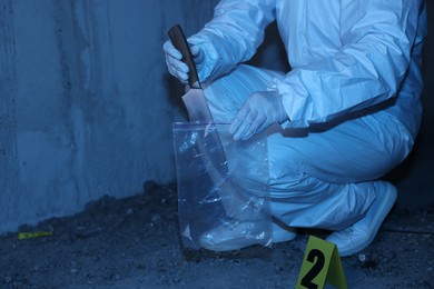 Photo of Forensic expert with evidence working at crime scene inside abandoned building, closeup. Space for text