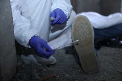 Photo of Forensic expert working at crime scene with dead body inside abandoned building, closeup