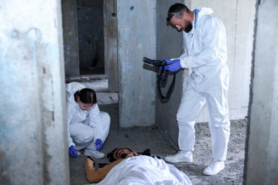 Photo of Forensic experts working at crime scene with dead body inside abandoned building