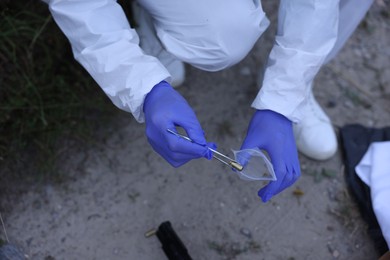 Photo of Forensic expert working at crime scene outdoors, top view