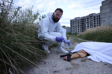 Photo of Forensic expert working at crime scene with dead body outdoors