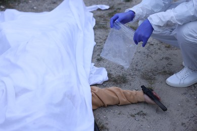 Photo of Forensic expert working at crime scene with dead body outdoors, closeup