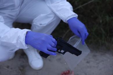 Photo of Forensic expert with evidence working at crime scene outdoors, closeup