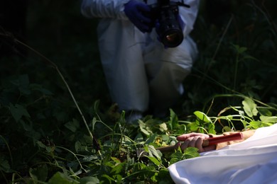 Photo of Forensic expert working at crime scene with dead body outdoors, closeup