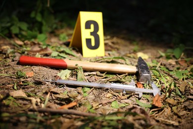 Photo of Forensic expertise. Crime scene with marker and evidences outdoors, closeup