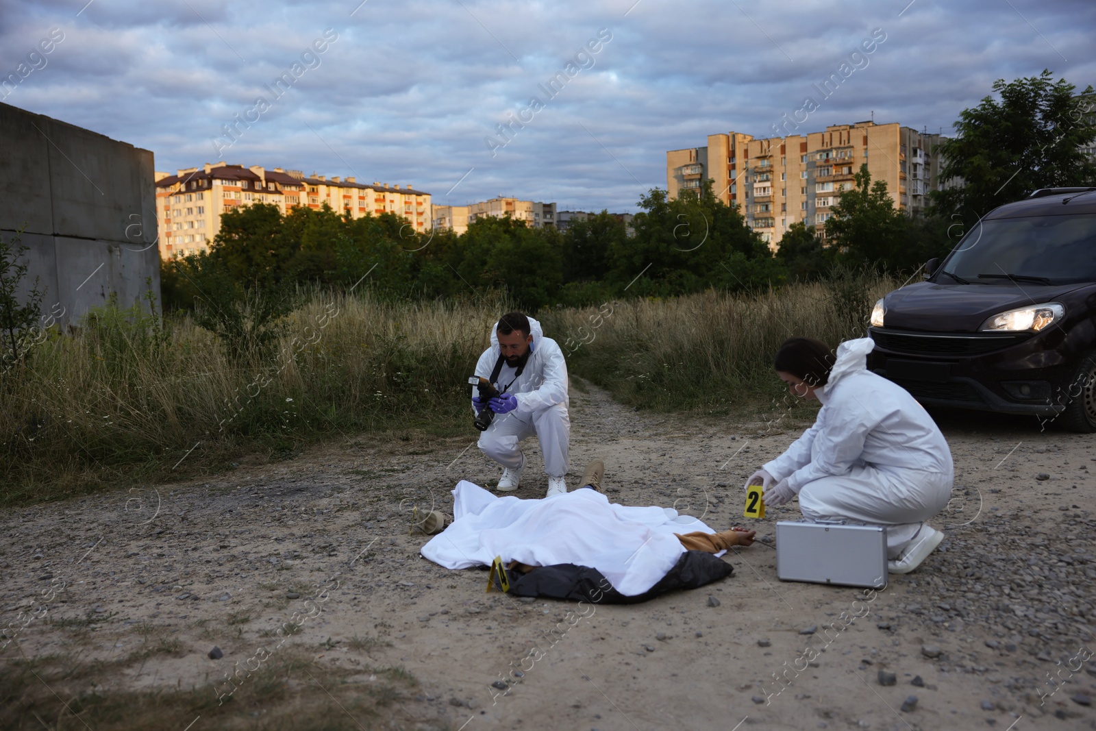Forensic experts working at crime scene with dead body outdoors, space for text Photo of Forensic experts working at crime scene with dead body outdoors, space for text
