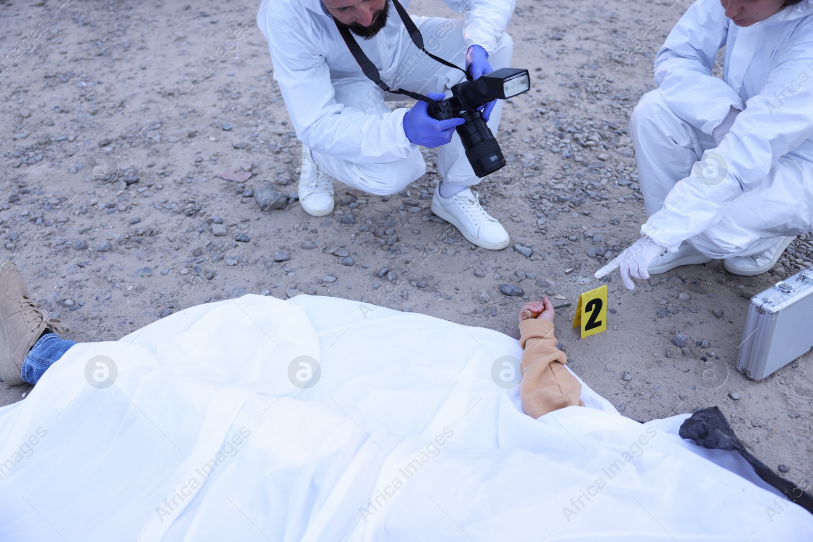 Forensic experts working at crime scene with dead body outdoors, closeup Photo of Forensic experts working at crime scene with dead body outdoors, closeup