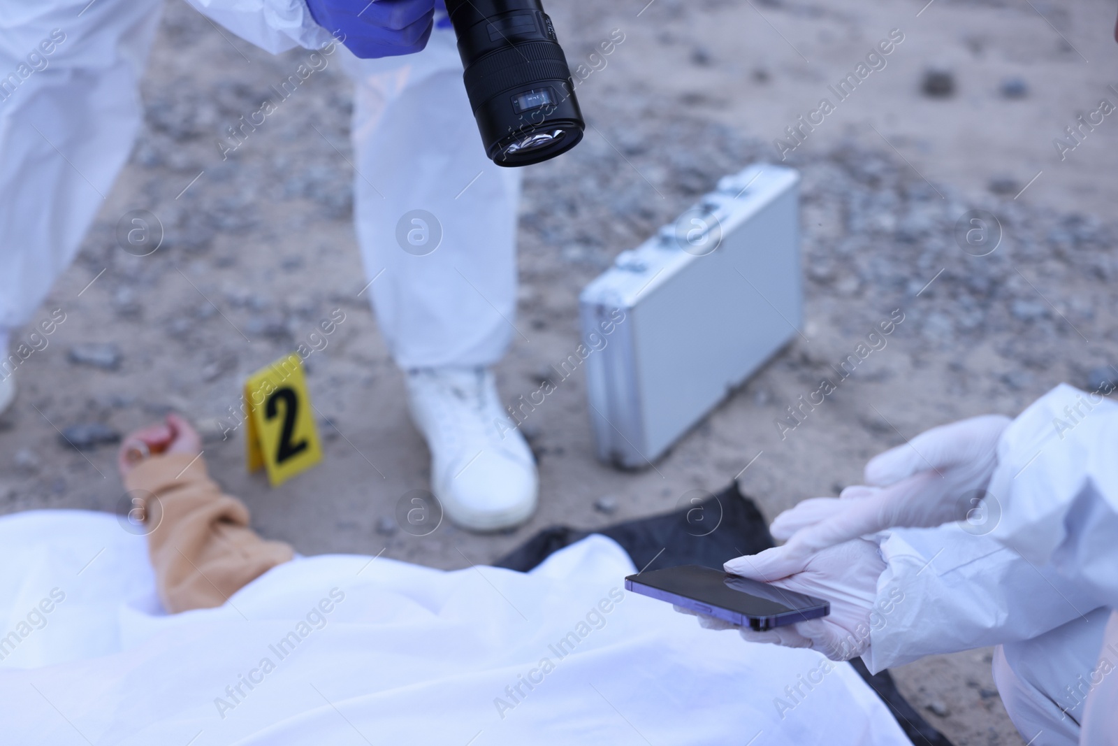 Photo of Forensic experts working at crime scene with dead body outdoors, closeup