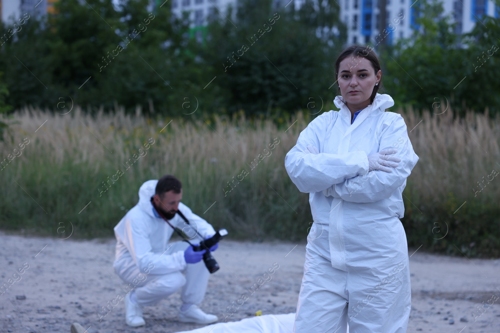 Photo of Forensic experts working at crime scene with dead body outdoors, selective focus