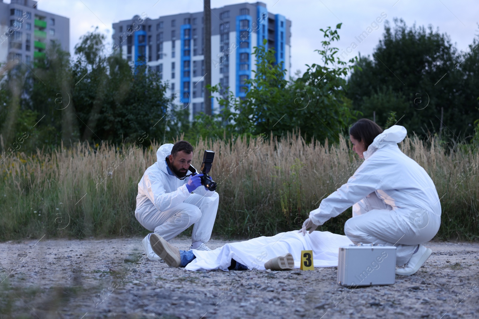 Photo of Forensic experts working at crime scene with dead body outdoors