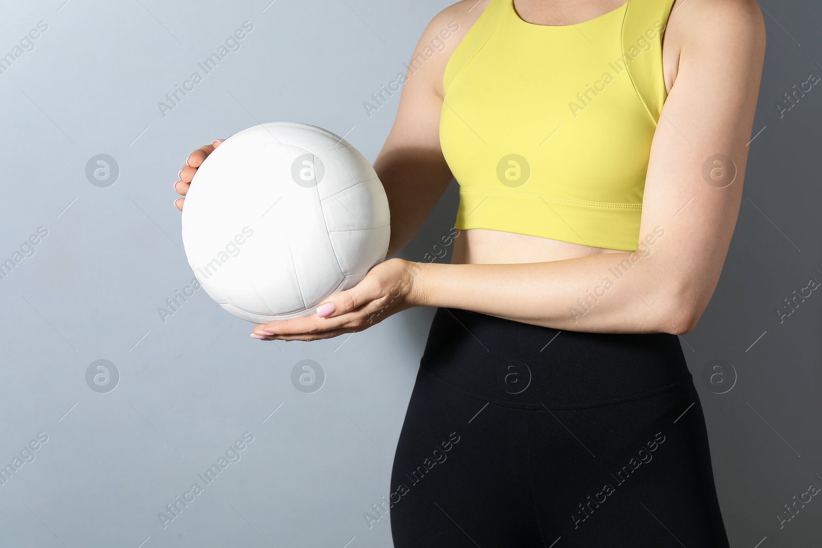 Photo of Woman with volleyball ball on light grey background, closeup