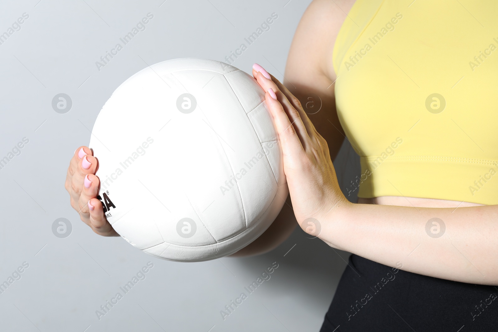 Photo of Woman with volleyball ball on light grey background, closeup