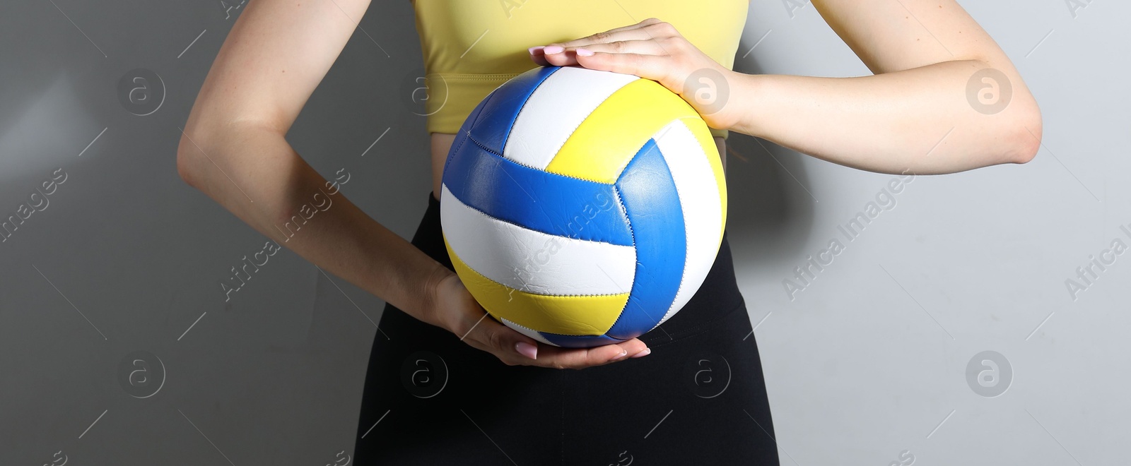 Photo of Woman with volleyball ball on light grey background, closeup