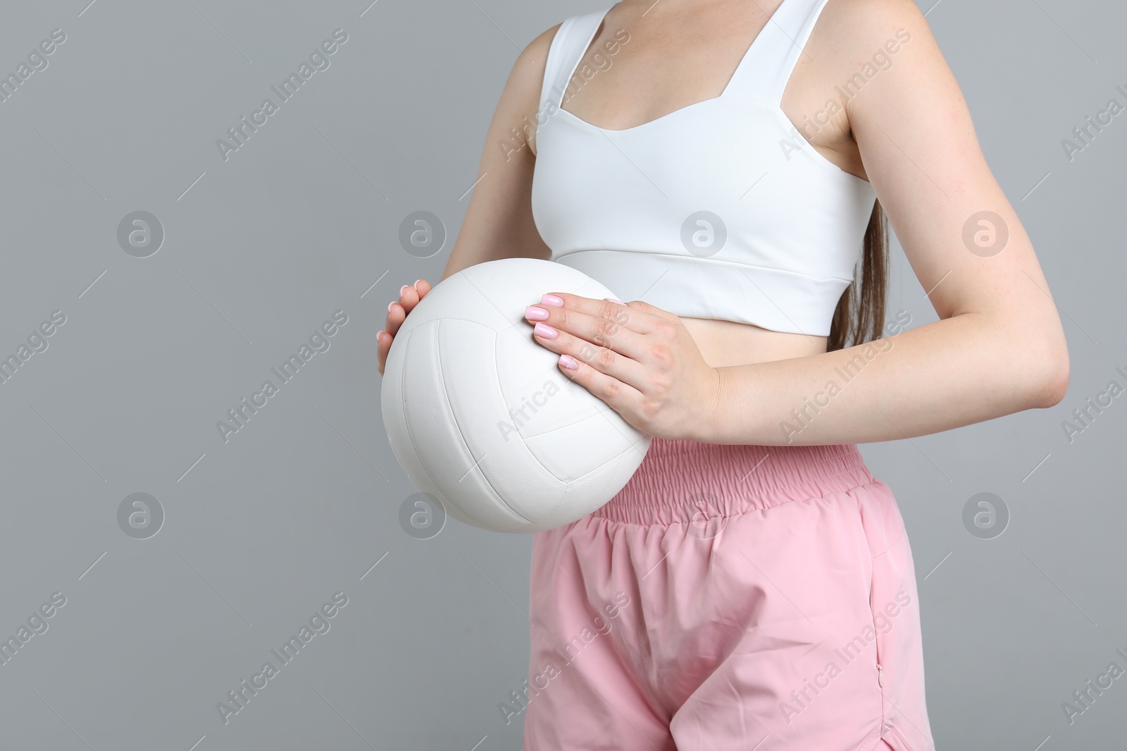 Photo of Woman with volleyball ball on light grey background, closeup. Space for text
