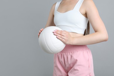 Photo of Woman with volleyball ball on light grey background, closeup. Space for text