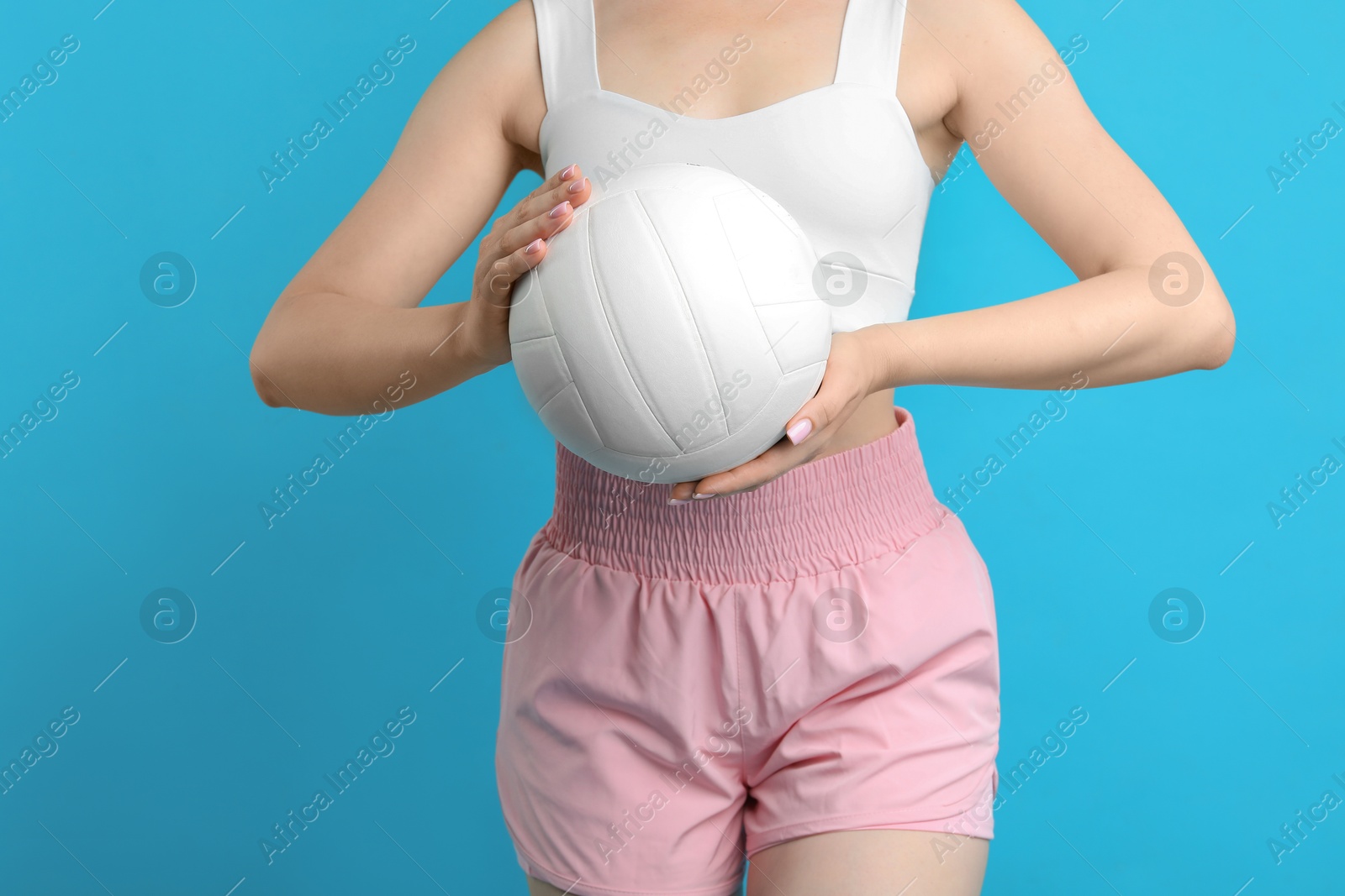 Photo of Woman with volleyball ball on light blue background, closeup