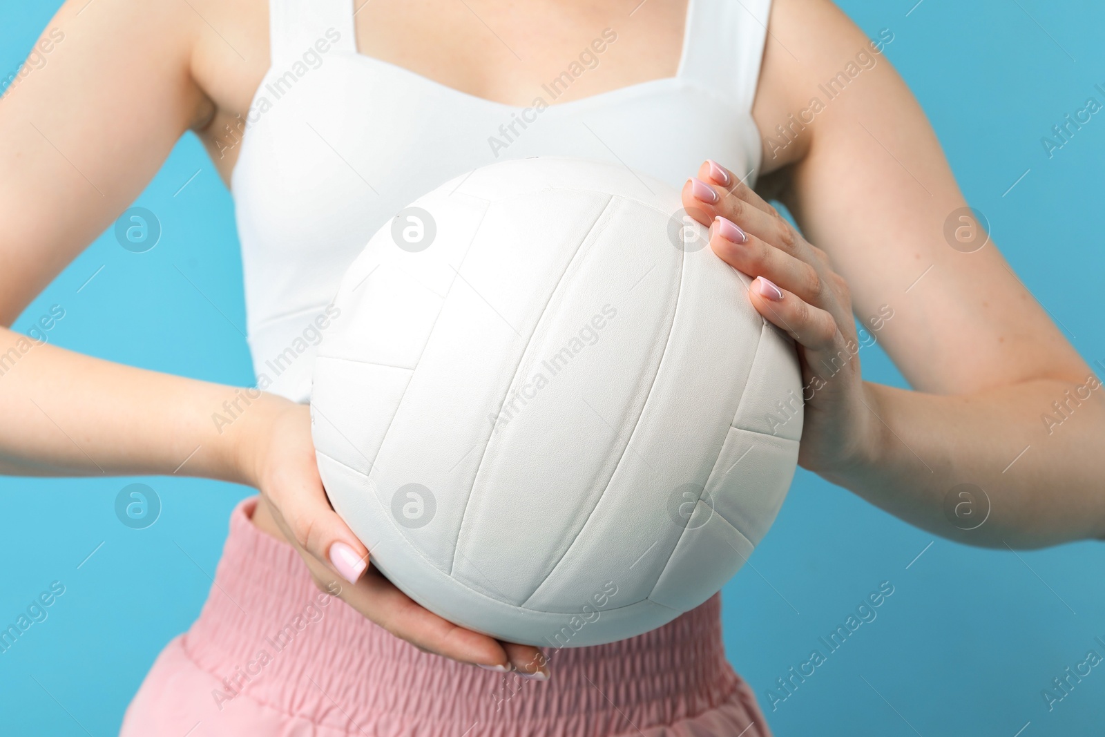 Photo of Woman with volleyball ball on light blue background, closeup