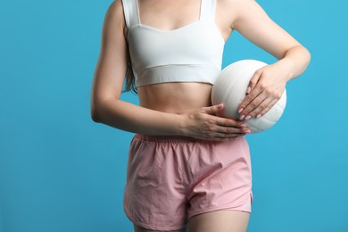 Photo of Woman with volleyball ball on light blue background, closeup