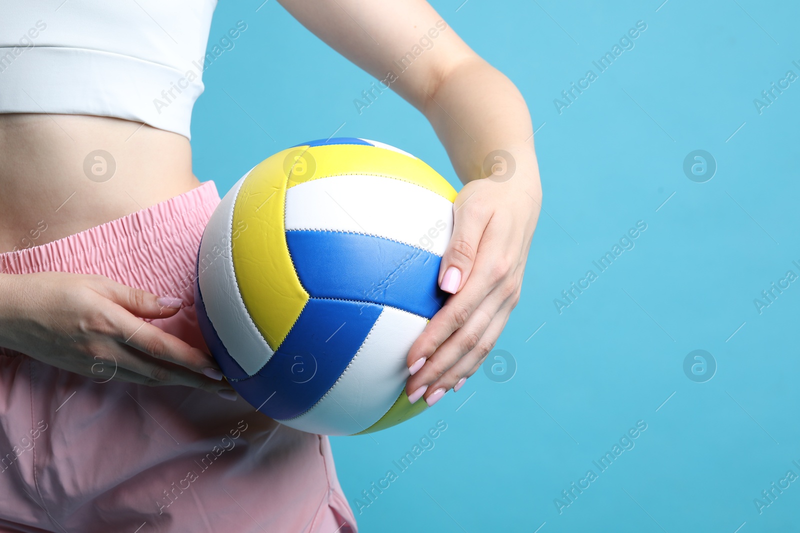 Photo of Woman with volleyball ball on light blue background, closeup. Space for text