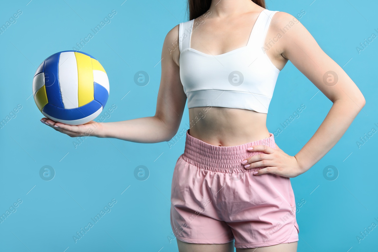 Photo of Woman with volleyball ball on light blue background, closeup