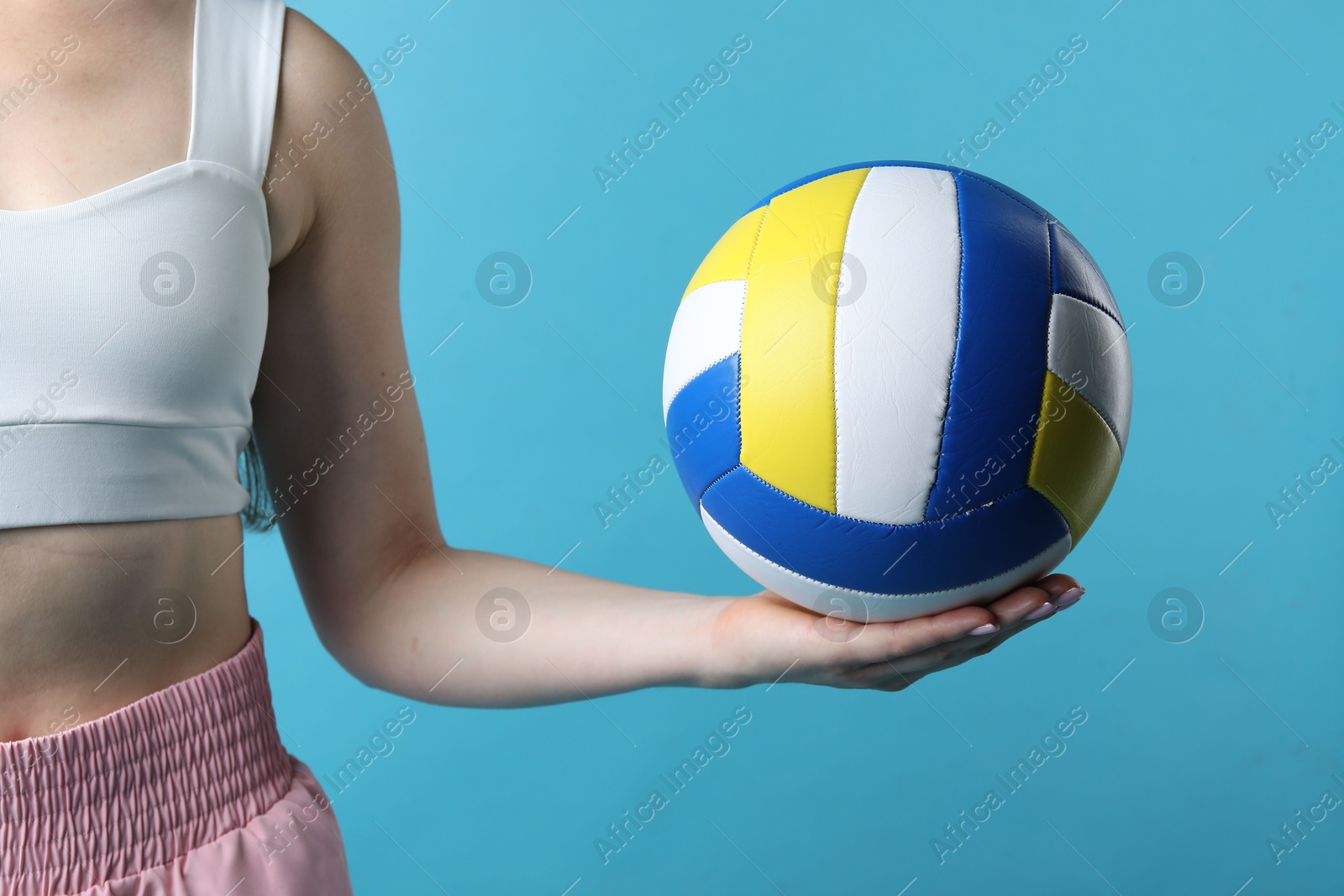 Photo of Woman with volleyball ball on light blue background, closeup