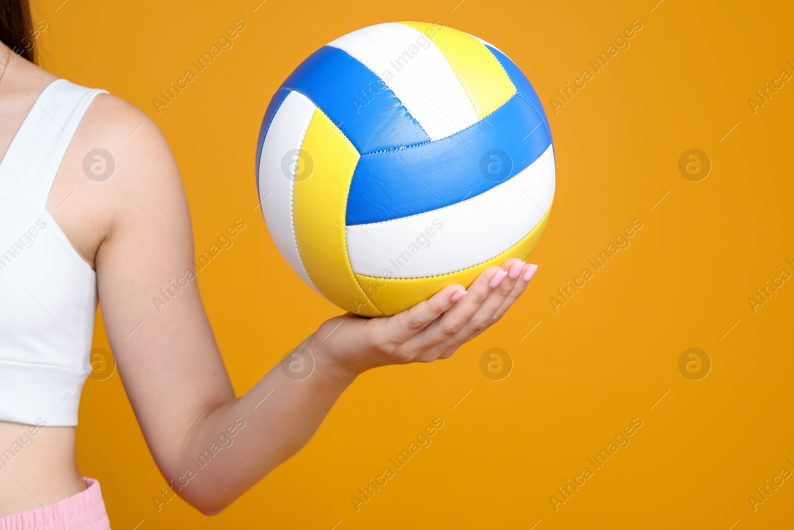 Photo of Woman with volleyball ball on orange background, closeup. Space for text