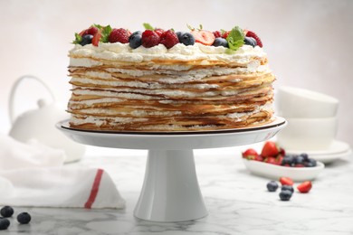 Photo of Delicious crepe cake with fresh berries on white marble table