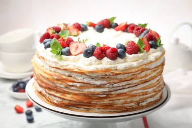 Photo of Delicious crepe cake with fresh berries on white table, closeup
