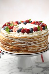 Photo of Delicious crepe cake with fresh berries on white marble table, closeup