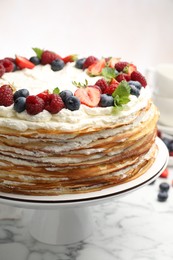 Photo of Delicious crepe cake with fresh berries on white marble table, closeup