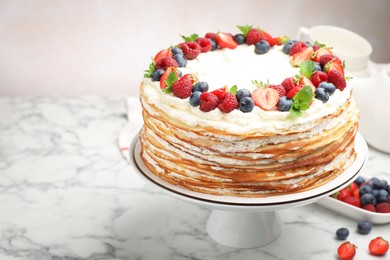 Photo of Delicious crepe cake with fresh berries on white marble table, space for text