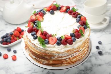 Photo of Delicious crepe cake with fresh berries on white marble table, closeup