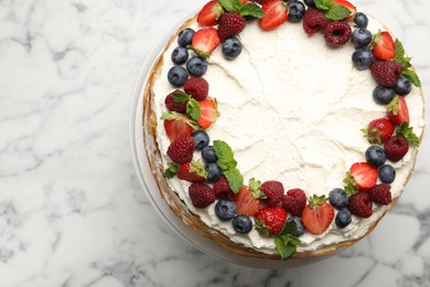 Photo of Delicious crepe cake with fresh berries on white marble table, top view. Space for text