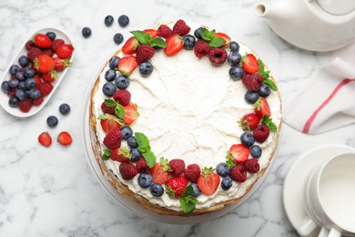 Photo of Delicious crepe cake with fresh berries on white marble table, flat lay