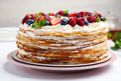 Photo of Delicious crepe cake with fresh berries on white wooden table, closeup