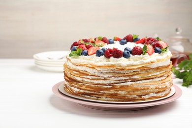 Photo of Delicious crepe cake with fresh berries on white wooden table, closeup. Space for text
