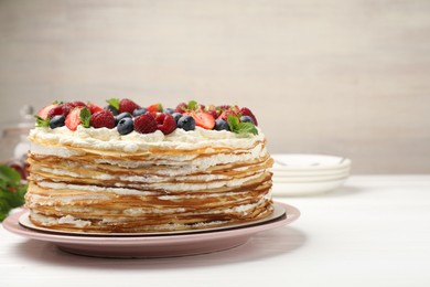 Photo of Delicious crepe cake with fresh berries on white wooden table, closeup. Space for text