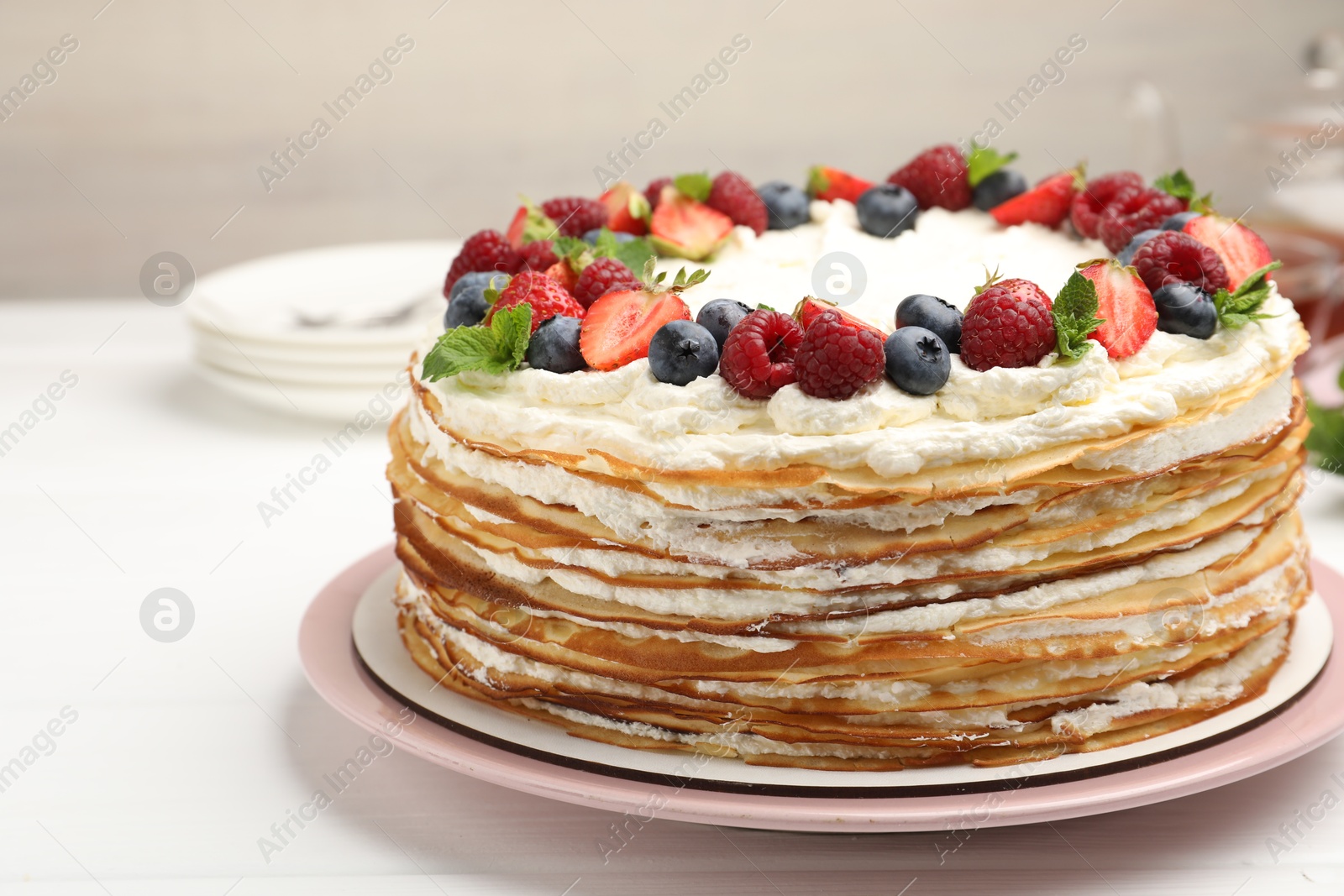 Photo of Delicious crepe cake with fresh berries on white table, closeup