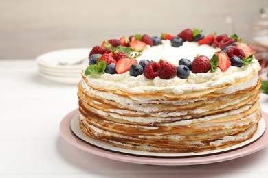 Photo of Delicious crepe cake with fresh berries on white table, closeup