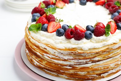 Photo of Delicious crepe cake with fresh berries on white table, closeup