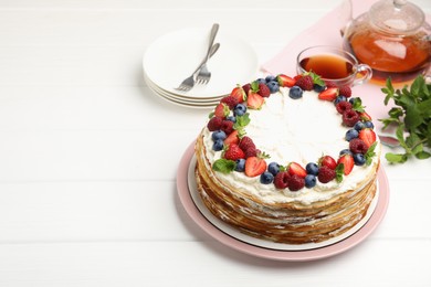 Photo of Delicious crepe cake with fresh berries served on white wooden table, space for text