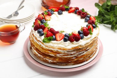 Photo of Delicious crepe cake with fresh berries served on white wooden table