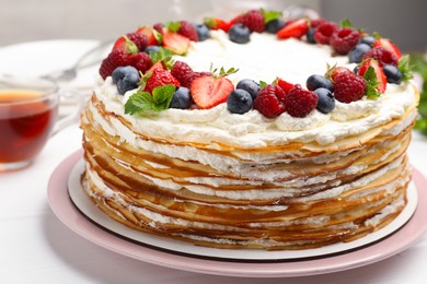 Photo of Delicious crepe cake with fresh berries on white table, closeup
