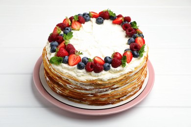 Photo of Delicious crepe cake with fresh berries on white wooden table
