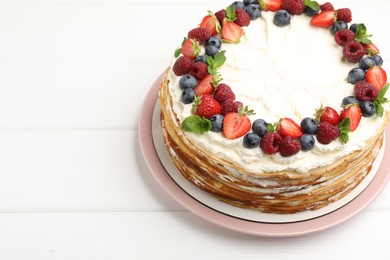 Photo of Delicious crepe cake with fresh berries on white wooden table, closeup. Space for text