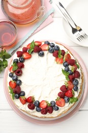 Photo of Delicious crepe cake with fresh berries served on white wooden table, flat lay