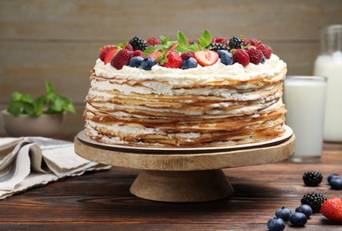Photo of Delicious crepe cake with fresh berries on wooden table